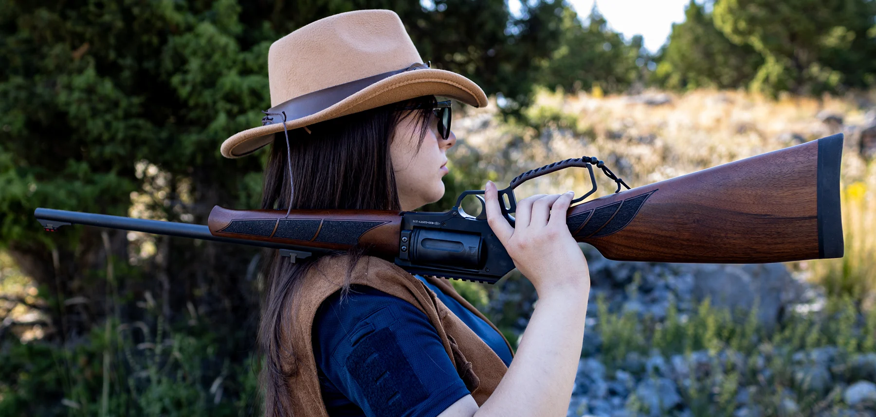 A hunter carrying a walnut-stock YNG rifle outdoors